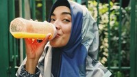 Pemilik nama asli Ratu Tika Bravani ini sedang asyik menikmati sebotol jus berwarna oranye. Foto: Instagram @tikabravani