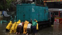 Banjir yang melanda beberapa daerah di India ini menyebabkan arus listrik di beberapa daerah tersebut padam. Polisi dibantu dengan warga lainnya terlihat mendorong truk genset untuk memasok listrik di daerah yang terendam banjir. Francis Mascarenhas/Reuters.