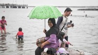 Meskipun hujan banyak pengunjung tetap datang untuk berwisata ke Pantai Ancol.