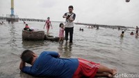 Tak sedikit pula orang dewasa ikut bermain air atau sekadar berfoto di pantai.
