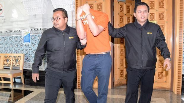 Mantan staf Najib menutup wajahnya saat dibawa ke pengadilan pada Senin (25/6) pagi