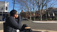 Ketika berlibur ke Australia, Ricky terlihat asyik menikmati pemandangan jalan ditemani secangkir kopi hangat. Foto: Instagram @komoricky
