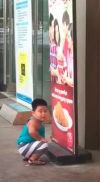 Gemas! Anak Kecil Ini Berusaha Memakan Ayam Goreng dari Papan Iklan