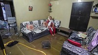 Seorang warga duduk di dalam rumahnya yang terendam banjir akibat curah hujan yang tinggi mengguyur beberapa daerah di India. Amit Dave/Reuters.