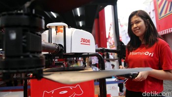 Seorang SPG memperkenalkan drone teranyar mereka yang bisa digunakan untuk mengangkut barang.