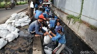 Sejumlah petugas Sudin Tata Air dan Sudin Sumber Daya Air Jakarta Utara membersihkan lumpur di saluran air yang tercemar limbah solar di Jalan Rorotan, Jakarta Utara, Selasa (26/6).