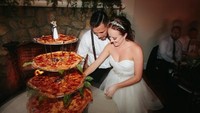 Yang satu ini sangat cocok untuk pencinta pizza. Empat loyang pizza dari ukuran terbesar hingga terkecil disusun dalam rak besi. Di atasnya tetap ada miniatur pengantin lho! Foto: Todd Good Photography