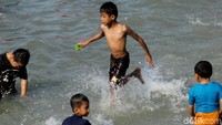 Anak-anak tampak asyik bermain dengan gembira di Pantai Ancol.