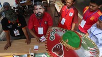 Para petugas memakai baju dan topeng pemain sepak bola.
