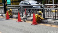 Pekerja membersihkan pembatas jalan sebelum dicat.