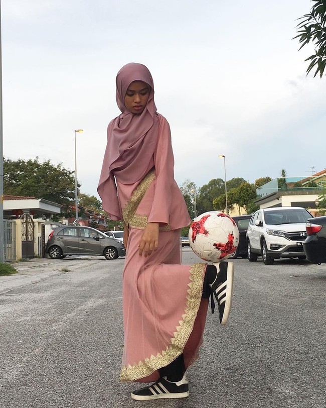 Sebuah video yang memperlihatkan wanita bermain free style street ball jadi viral. Tampilan wanita itu sangat unik, ia memakai baju kurung dan hijab tapi jago bermain bola. Foto: Instagram/Qhouirunnisa