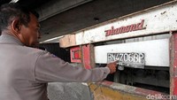 Pihak kepolisian menunjukkan plat nomor truk kontainer yang terguling di Tomang.