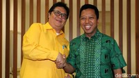 Dua ketua umum partai politik itu berjabat tangan sambil tersenyum.