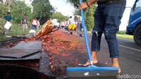 Petugas lalu lintas dibantu warga sekitar masih berupaya membersihkan sambel dan kecap yang tumpah di badan jalan. Foto: (Yahya-detik)