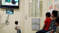 Tampak beberapa anak-anak sedang menunggu kedatangan Melania Trump ke Pusat Perlindungan Anak-anak Imigran Ilegal sambil menonton televisi. Leah Millis/Reuters.