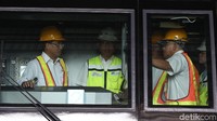 Dia mengenakan kemeja warna putih dan bercelana bahan hitam.