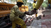 Petugas menurunkan konblok dari atas truk.