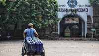 Penjual air bersih melintas di depan komplek makam Mbah priuk.