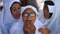Seorang ibu tampak memanjatkan doa untuk keluarganya yang jadi korban. 