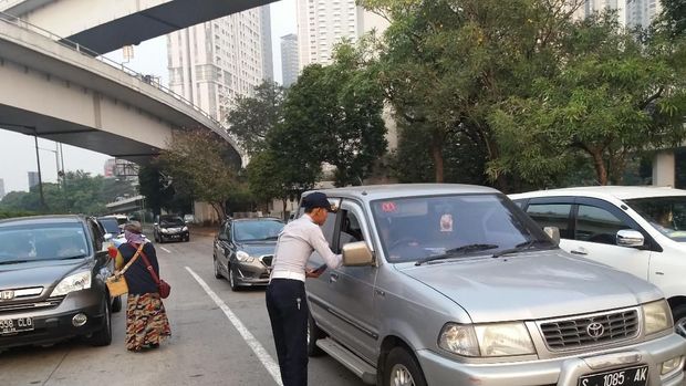 Petugas  membagi-bagikan brosur perluasan ganjil genap kepada pengemudi.