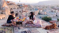 Liburan ke Capadoccia, dengan bangunan rumah yang unik serta balon udara yang menghiasi langit. Keduanya tampak sedang menikmati makan mewah dan romantis. Foto: Instagram @rachelvennya