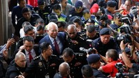 Tampak mengenakan jas warna biru tua dan dasi merah, Najib dikawal banyak personel Komisi Antikorupsi Malaysia (MACC) saat berjalan masuk ke ruang sidang. Foto: REUTERS/Lai Seng Sin