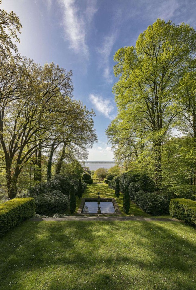 Bagian belakang rumah yang sangat luas, dipenuhi rerumputan serta pohon-pohon rindang. Lewat pekarangan belakang ini, penghuni bisa melihat keindahan pemandangan sungai Elbe yang disukai sekaligus dibenci Karl Lagerfeld. Foto: Dok. Engel & Volkers