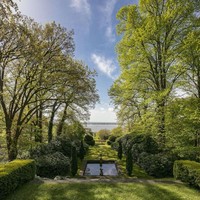 Bagian belakang rumah yang sangat luas, dipenuhi rerumputan serta pohon-pohon rindang. Lewat pekarangan belakang ini, penghuni bisa melihat keindahan pemandangan sungai Elbe yang disukai sekaligus dibenci Karl Lagerfeld. Foto: Dok. Engel & Volkers