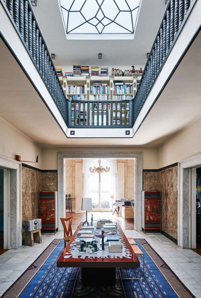 Bagian tengah rumah ditata dengan gaya yang terinspirasi dari Roma. Kesan mewah muncul dari lantai marmer, furnitur kayu juga karpet biru bermotif geometris. Ruangan ini terhubung dengan perpustakaan di atasnya. Foto: Dok. Engel & Volkers