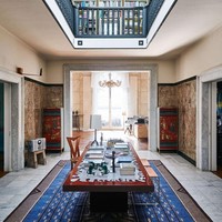 Bagian tengah rumah ditata dengan gaya yang terinspirasi dari Roma. Kesan mewah muncul dari lantai marmer, furnitur kayu juga karpet biru bermotif geometris. Ruangan ini terhubung dengan perpustakaan di atasnya. Foto: Dok. Engel & Volkers