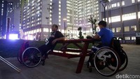 Dua atlet Asian Para Games menikmati suasana malam di salah satu taman di kawasan Wisma Atlet Kemayoran.