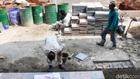 Pekerja sibuk memasang lantai trotoar. 