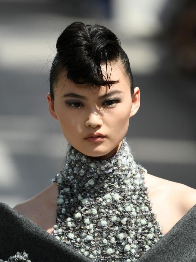 Dalam peragaannya, Chanel mengangkat spirit rock n roll ala Elvis untuk gaya rambut para modelnya. Inspirasi tersebut lalu menjelma dalam hair-do bergaya jambul yang menggulung bak molen. (Foto: Getty Images)