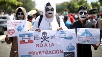 Berbagai poster yang berisi penolakan privatisasi air dibawa oleh para warga dalam melakukan aksi demo yang telah berlangsung selama satu bulan ini. Jose Cabezas/Reuters.