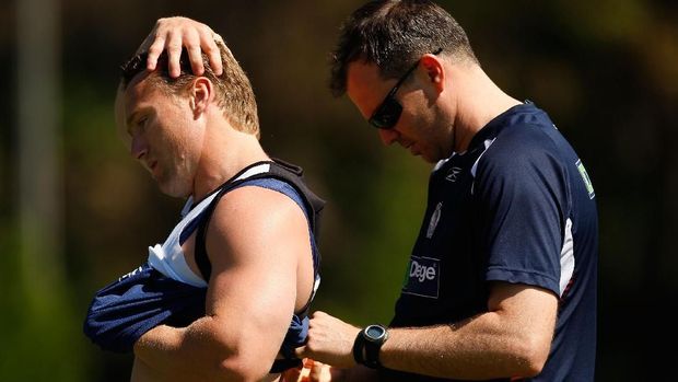 Pelatih sedang membantu pemain memasang 'smart vest' yang berfungsi sebagai fitness tracker.