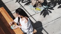 Disorot oleh cahaya cerah dari matahari, Febby berpose natural sambil menikmati secangkir kopi di sebuah kafe kekinian. Foto: Instagram @febbyrastanty