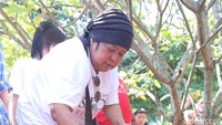Suti Karno menyiram makam Pak Tile dengan air. Foto: Ismail/detikHOT