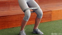 Yang kedua adalah half squat side walk. Naikkan resistance band ke paha, lalu turunkan tubuhmu membentuk pose squats. (Foto: Frieda Isyana Putri/detikHealth)