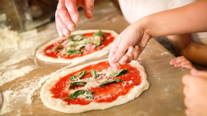 Preparing Classical Pizza Margherita. Cooks add grated parmesan cheese. Selective focus