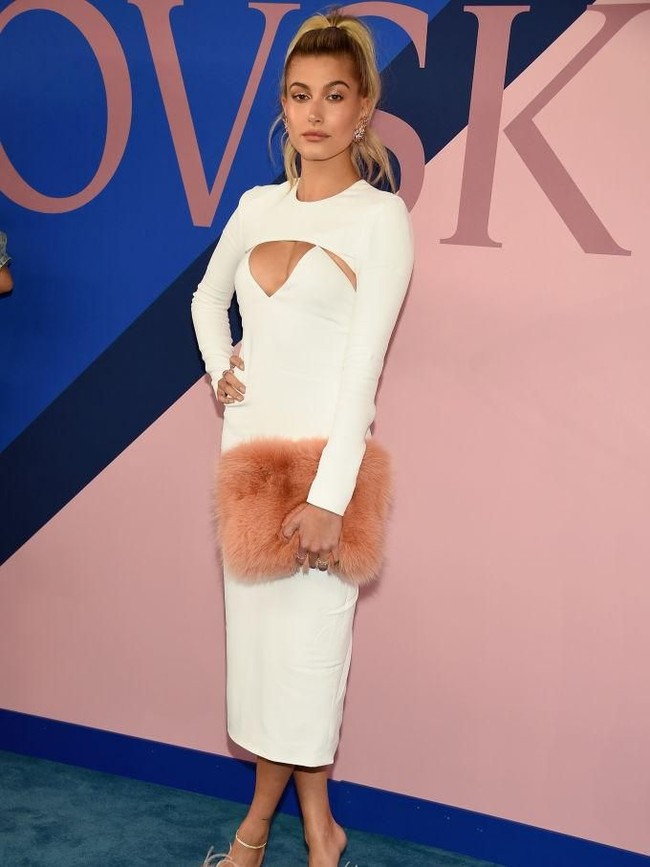 Hadir di CFDA Awards 2017, Hailey Baldwin memilih gaun putih ketat dengan detail cut-out di area dada, dengan tas dan sendal berbulu sebagai pemanis. (Foto: Getty Images)