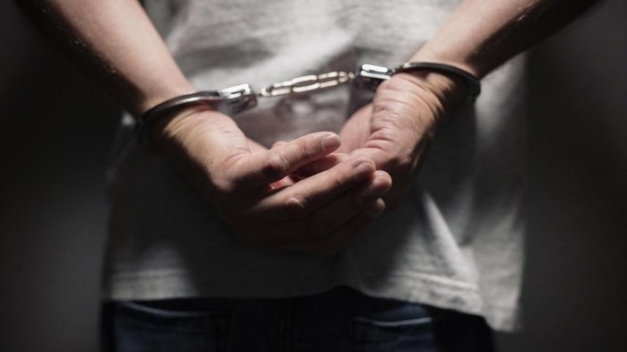 Arrested man in handcuffs with handcuffed hands behind back