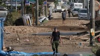 Warga Kurashiki, Okayama mulai menyisir jalanan yang dipenuhi lumpur yang dibawa banjir. Sejauh ini korban tewas akibat banjir mencapai sedikitnya 85 orang. Foto: AFP PHOTO/JIJI PRESS