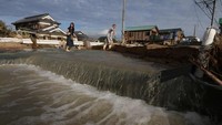 Sebagian jalanan di Kurashiki, Okayama masih digenangi banjir. Tampak dalam foto saat warga setempat harus melewati jalanan yang digenangi banjir. Ratusan rumah dilaporkan hancur dan rusak akibat banjir. Foto: AFP PHOTO/JIJI PRESS
