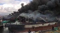 Kapal ikan yang terbakar dimensinya cukup besar. Tampak asap hitam tebal membububung ke langit.