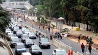 Para pejalan kaki melintas di depan proyek trotoar di Jalan Sudirman.