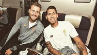 Kalau ini senyum bahagia Mignolet ditemani Roberto Firmino saat akan terbang ke Hong Kong. Perjalanan panjang pemain klub bola Liverpool ini ditemani sebotol minuman di meja. Foto: Instagram 22mignolet22