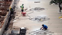 Pekerja menyelesaikan pemasangan konblok.