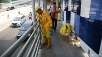 Para pekerja tampak sibuk menggoreskan kuas di pagar JPO.