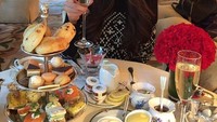 Wah, ternyata Kezia gemar afternoon-tea. Ditemani segelas champagne, Kezia menikmati hidangan kue dari afternoon-tea yang dipesannya. Ada sandwich, macaron, hingga scone. Foto: Instagram @keziatoemion