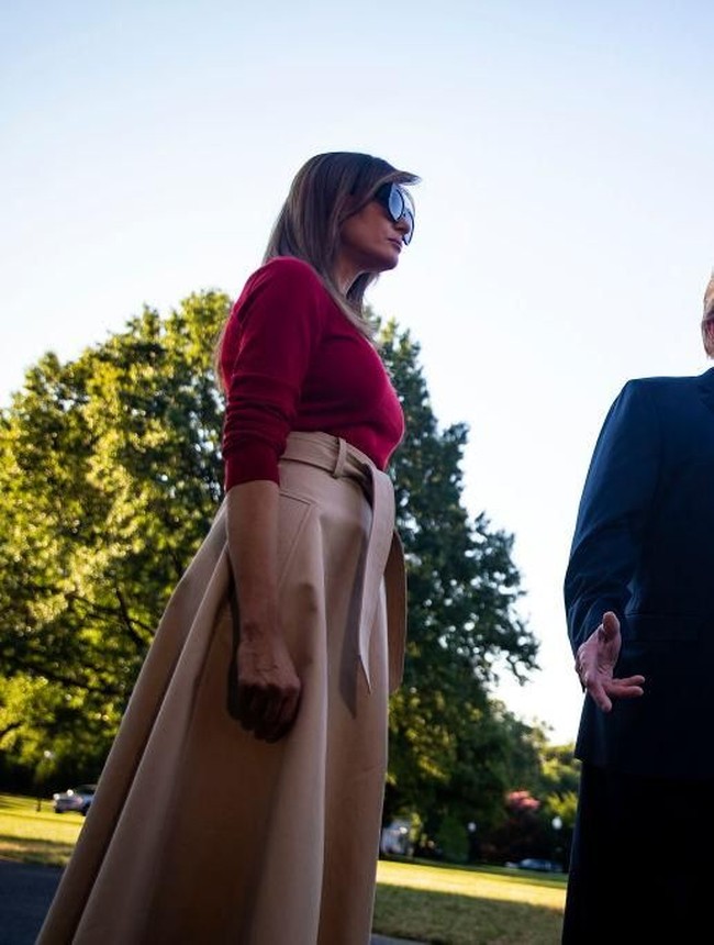 Melania Trump muncul dalam balutan atasan merah lengan panjang yang dipadukan dengan rok flare coklat bersabuk. (Foto: Getty Images)